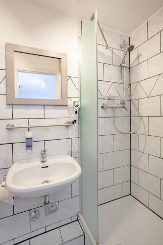 a white bathroom with a sink and a shower at Relax Hotel & SPA Stuttgart in Stuttgart