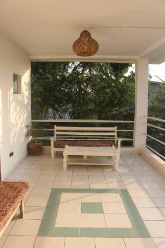 a white bench sitting on a screened in porch at Maison Tikani in Cotonou