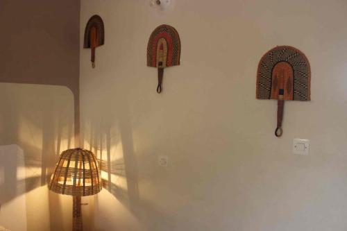a wall with three wooden hats on a wall at Maison Tikani in Cotonou