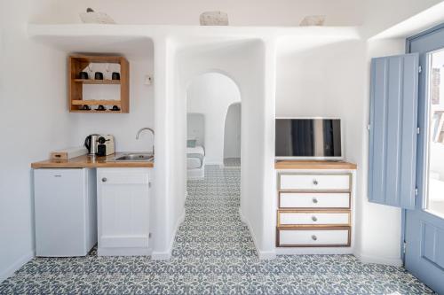 a kitchen with white cabinets and a tile floor at Luna Santorini Suites in Pirgos