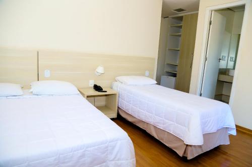 two beds sitting next to each other in a room at VOA Hotel Rezende in Lambari