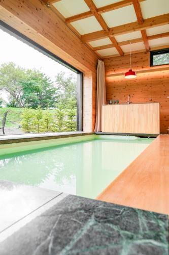 a swimming pool in a wooden house with a large window at Kita Karuizawa Morino Takibi Pool Villa with Sauna in Tsumagoi