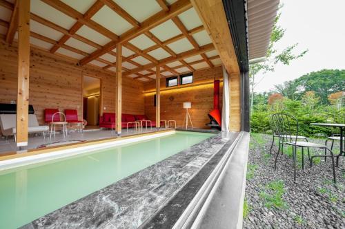 an indoor pool with chairs and tables in a house at Kita Karuizawa Morino Takibi Pool Villa with Sauna in Tsumagoi