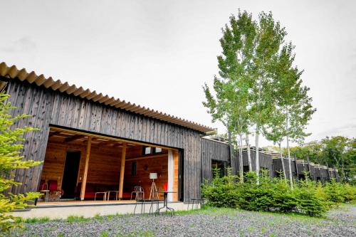a house with a wooden facade and a tree at Kita Karuizawa Morino Takibi Pool Villa with Sauna in Tsumagoi