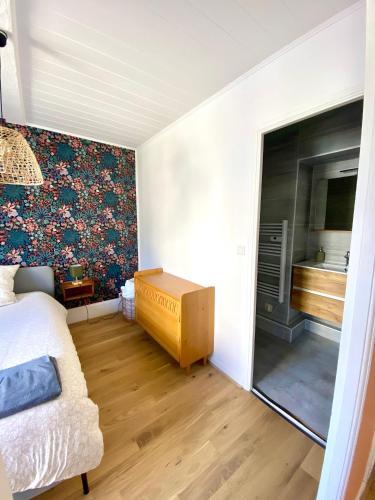 - une chambre avec un lit et un mur orné d'un papier peint floral dans l'établissement Dijon hypercentre *Le Berbisey*, à Dijon