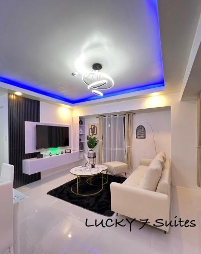 a living room with a white couch and a tv at Lucky 7 Suites in Manila