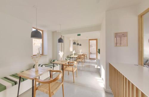 a dining room with tables and chairs and a staircase at La Maison Gaïa Hôtel & Spa in Torreilles