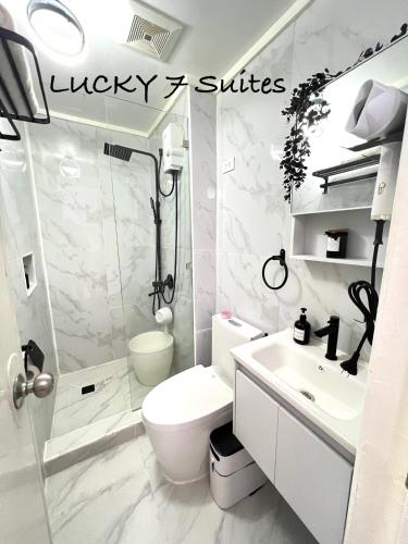 a bathroom with a toilet and a shower and a sink at Lucky 7 Suites in Manila
