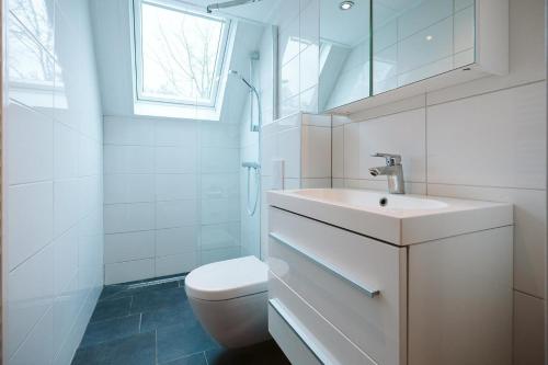 a white bathroom with a sink and a toilet at Jonkerstee 59 - Ouddorp in Ouddorp