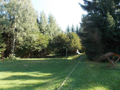 a green field with trees and a sign in the grass at Srubová chata Oaza 1 in Trojanovice
