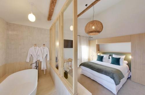 a bedroom with a tub and a bed and a bath room at La Maison Gaïa Hôtel & Spa in Torreilles