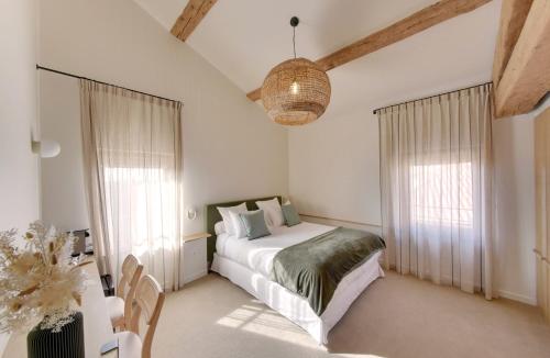 a bedroom with a bed and two windows at La Maison Gaïa Hôtel & Spa in Torreilles