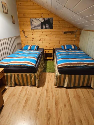 two beds in a room with wooden walls at Domek Domino in Korbielów