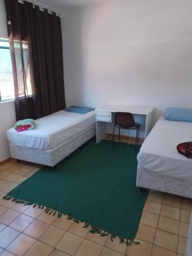 a room with two beds and a green rug at Hotel Pousada Liberdade in Pindamonhangaba
