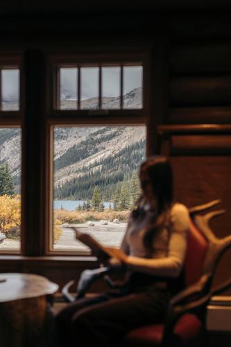 a woman sitting in a chair with a laptop at The Lodge at Bow Lake in Lake Louise