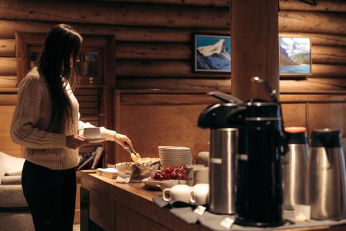 a woman standing in a kitchen preparing food at The Lodge at Bow Lake in Lake Louise