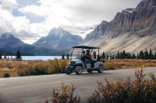 a golf cart driving down a road in the mountains at The Lodge at Bow Lake in Lake Louise