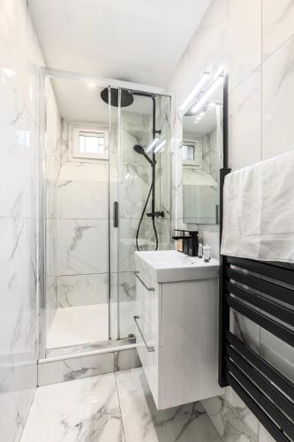 une salle de bain blanche avec une douche et un lavabo dans l'établissement Splendide appartement Paris 18eme 6P, à Paris