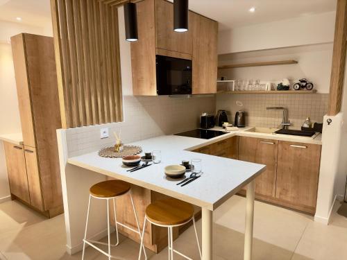 une cuisine avec un îlot blanc et deux tabourets dans l'établissement Évasion Bohème - Studio avec terrasse au cœur de Cannes, à Cannes