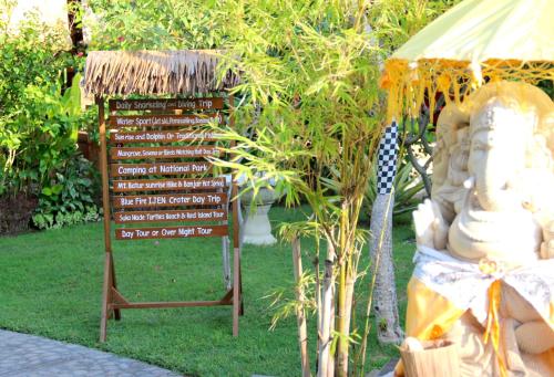 a sign in the grass next to a sign with a tree at Kubuku Eco Dive Lodge and Yoga in Pemuteran