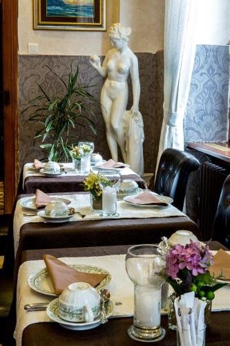 a set of tables in a restaurant with a statue at Logis Hôtel Restaurant La Tête Des Faux in Le Bonhomme