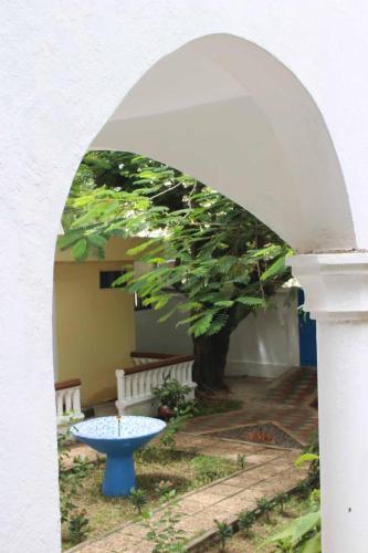 an archway with a blue table in front of a tree at Maison Tikani in Cotonou