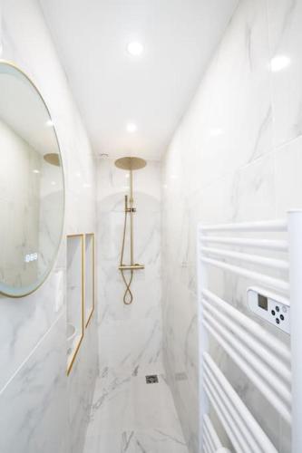 La salle de bains est pourvue d'un miroir et de murs en marbre blanc. dans l'établissement Beau Studio Rénové - Lille JB Lebas, à Lille