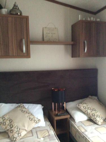 a bedroom with two beds and wooden cabinets at Newquay Haven caravan 42x14 with Ocean Views in New Quay