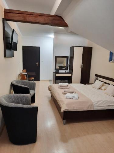 a bedroom with a bed and two chairs and a mirror at apartmán Sienna in Bešeňová