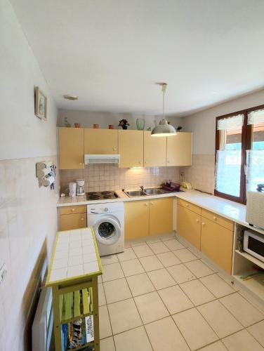 une cuisine avec des armoires jaunes et un lave-linge dans l'établissement soleil catalan 50m2 , 2km mer jardin wifi parking 2ch 4pers chéque vacance, à Elne