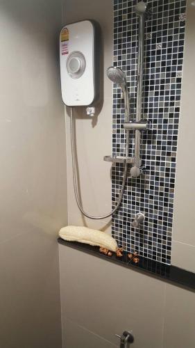 a shower in a bathroom with a black tiled wall at JK LIVING Hotel And Service Apartment in Chachoengsao