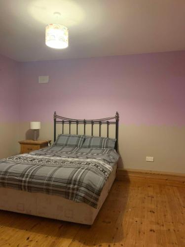 a bedroom with a bed and a purple wall at Global Guest Ireland in Williamstown