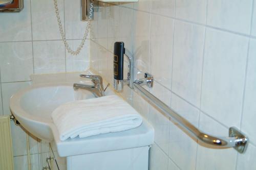 a white bathroom with a sink and a towel at Hotel Rahlstedter Hof in Hamburg