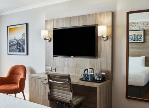 a hotel room with a bed and a desk with a television at Leonardo Edinburgh Murrayfield in Edinburgh