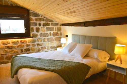 1 dormitorio con 1 cama grande y pared de piedra en La casa de la abuela Gabina, Duruelo de la Sierra - 12 personas, en Duruelo de la Sierra