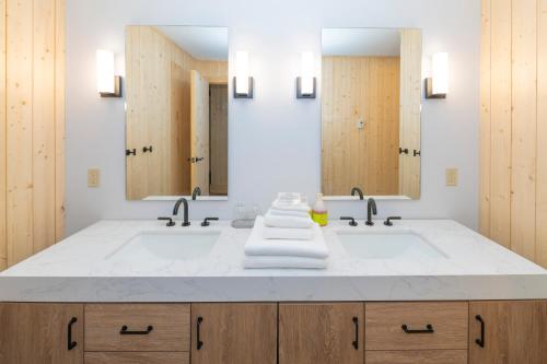 a bathroom with two sinks and two mirrors at The Lodge at Bow Lake in Lake Louise