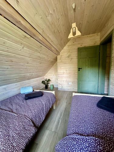 two beds in a room with wooden walls at Domki pod Aniołem in Huta