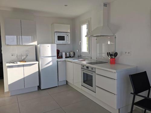 une cuisine blanche avec des appareils électroménagers blancs et une fenêtre dans l'établissement Appartement baie des anges vue sur mer, garage, à La Ciotat