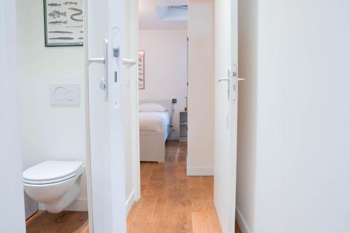- une salle de bains blanche pourvue de toilettes et d'un lit dans l'établissement Loft Petion Dog friendly, à Paris