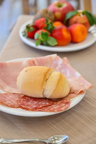 a sandwich on a plate on a table with fruit at Albergo Atlantic in Ischia