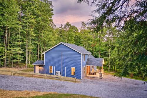 a blue house in the middle of the forest at Benezette Cabin with Hot Tub, Grill and Mtn Views in Benezette
