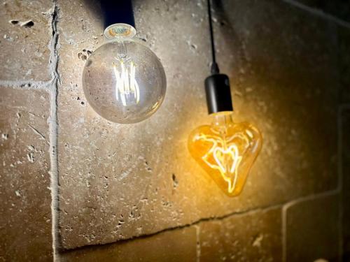a light bulb and a glass light fixture on a brick wall at Splendide Loft avec Jacuzzi et Cinema - Cap d'Agde in Agde