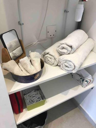 - une étagère blanche avec des serviettes et un bol dans l'établissement La Maisonnette T2 charmant jardin parking La Cadière d'Azur 1 à 4 personnes, à La Cadière-dʼAzur