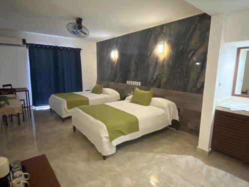 a hotel room with two beds and a table at Hotel D Marco Exxpres in Palenque