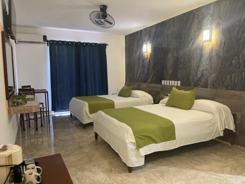 a hotel room with two beds with green sheets at Hotel D Marco Exxpres in Palenque