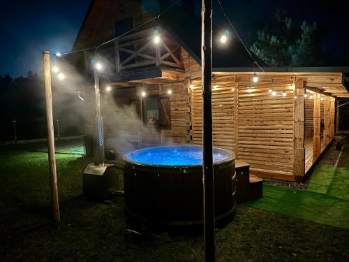 a hot tub in front of a wooden house at night at Sielankowe Pole in Józefów