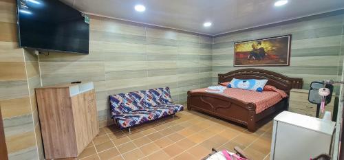 a room with a bed and a chair and a television at Hotel y Parque Turístico Navar City in Villavicencio