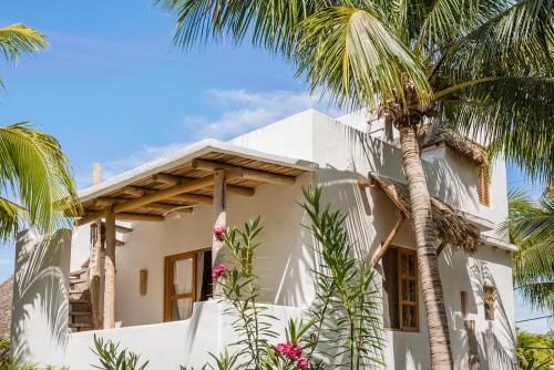 a white house with palm trees in front of it at Holbox island Casa Impala in Holbox Island