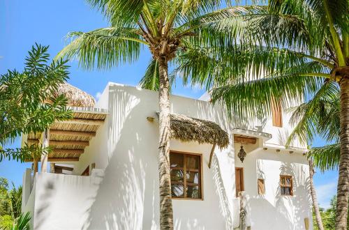 a white house with palm trees in front of it at Holbox island Casa Impala in Holbox Island