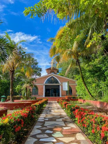 a walkway leading to a building with palm trees and flowers at Hotel y Parque Turístico Navar City in Villavicencio